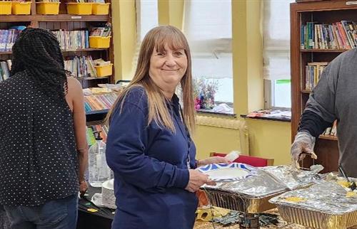 A picture of teacher, Mrs. Purdue, holding a plate in a line for lunch.